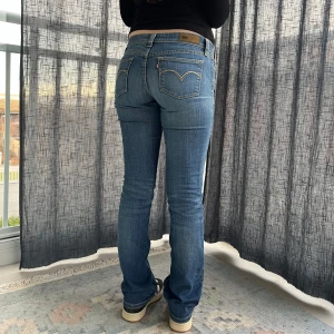 Lågmidjade jeans från Levi's -  Blåa Levi's jeans i mycket bra skick. De är tighta, bootcut och har en låg midja. De är i Modellen demi curve bootcut skinny. Storlek 27 Midjemått 38 cm Grenmått 18 cm innerbenslängd 82 cm