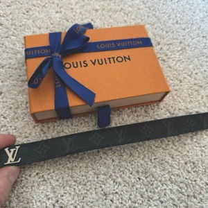 Svart Louis Vuitton Armband - Säljer ett snyggt svart armband från Louis Vuitton i skinn med det klassiska LV-mönstret. Kvitto finns, pris ej hugget i sten.