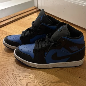 Nike Air Jordans i svart och blått - Säljer ett par snygga Nike Air Jordans i svart och blått. Skorna har en klassisk design med snörning och en bekväm passform. Perfekta för både vardag och fest! De är i bra skick med lite slitage på sulan.