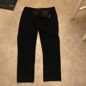 Svarta byxor från Gina Tricot - Snygga svarta byxor från Gina Tricot i storlek 36. De har en klassisk design med knappar framtill och en rak passform. Perfekta för både vardag och fest! 🖤
