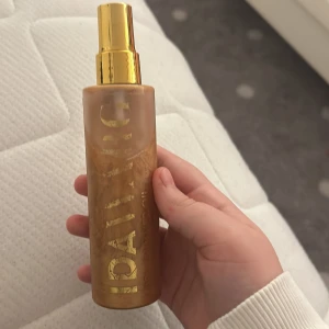 Gyllene shimmerolja från Ida Warg - Säljer en lyxig gyllene shimmerolja från Ida Warg. Perfekt för att ge huden en glittrande och solkysst look. Flaskan har en elegant design med en praktisk sprayfunktion och en glansig guldfärgad kork. Perfekt för fest eller vardag när du vill känna dig extra glamorös! ✨ mer än halva flaskan full!