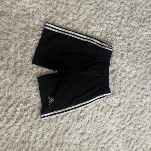 Säljer ett par svarta Adidas shorts i storlek 164. De har de klassiska tre vita ränderna längs sidorna och är perfekta för träning eller fotboll. Materialet är lätt och andas bra, vilket gör dem bekväma att bära under varma dagar. Passar perfekt för sommarens aktiviteter! Helt nya säljer pga fel storlek för mig 