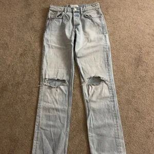 Ljusa jeans från Zara - Säljer ett par ljusa jeans från Zara i storlek EUR 36. De har en avslappnad straight fit med mid waist och med slitna detaljer på knäna för en trendig look. Perfekta för vardagsbruk och kan stylas med allt från sneakers till klackar. 