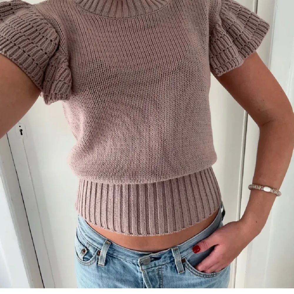 Säljer en superfin beige stickad topp med volangärmar. Den är croppad och har en ribbad kant nertill som ger en snygg passform. Perfekt för både höst och vinter! 🧶✨. Tröjor & Koftor.