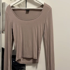 Beige långärmad topp - Säljer en stilren beige långärmad topp med rund halsringning. Perfekt för lager-på-lager eller som den är. Enkel och mångsidig design.