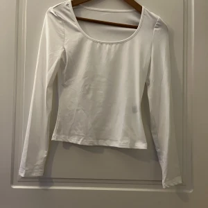 Vit långärmad topp - Säljer en stilren vit långärmad topp med rund halsringning. Perfekt för lager-på-lager eller att bära som den är. Enkel och mångsidig design.passar lika bra till jeans, kjol, kostymbyxor & shorts. Skrynkelfri 