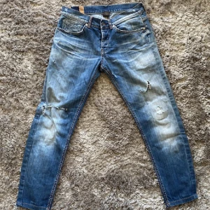Blå jeans med slitningar - Snygga blå jeans med coola slitningar och en vintage look. De har en klassisk femficksdesign och en knappgylf. Perfekta för en avslappnad stil.