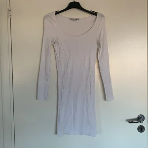 Vit ribbad klänning från 157 - Säljer en stilren vit ribbad klänning från 157 i storlek XS. Klänningen har en tight passform och långa ärmar, perfekt för en minimalistisk look. Den är enkel och elegant, vilket gör den lätt att matcha med olika accessoarer.