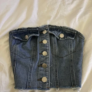 Jeans korsett med knappar - Snygg jeans korsett med knappar framtill. Den har en elastisk baksida för bättre passform och fram ”fickor”. Knappt använd.