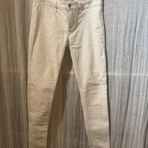Vita super skinny jeans från Hollister - Säljer ett par vita super skinny jeans från Hollister. De har en tight passform och är tillverkade i ett mjukt bomullsmaterial. Perfekta för en stilren look med klassiska femficksdetaljer och knappstängning.
