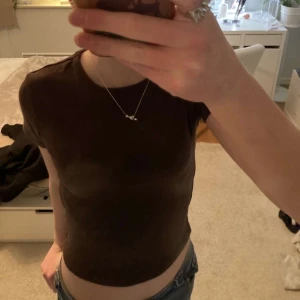 Brun  croppad T-shirt  - Säljer en brun croppad t-shirt med korta ärmar. Perfekt för en avslappnad stil och kan enkelt matchas med jeans eller kjol. Passar även bra som xs!