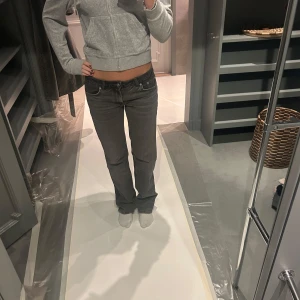 Grå jeans med låg midja - Snygga grå jeans med låg midja och bootcut-stil. Perfekta för en avslappnad look. De har en klassisk design med fem fickor och en bekväm passform.