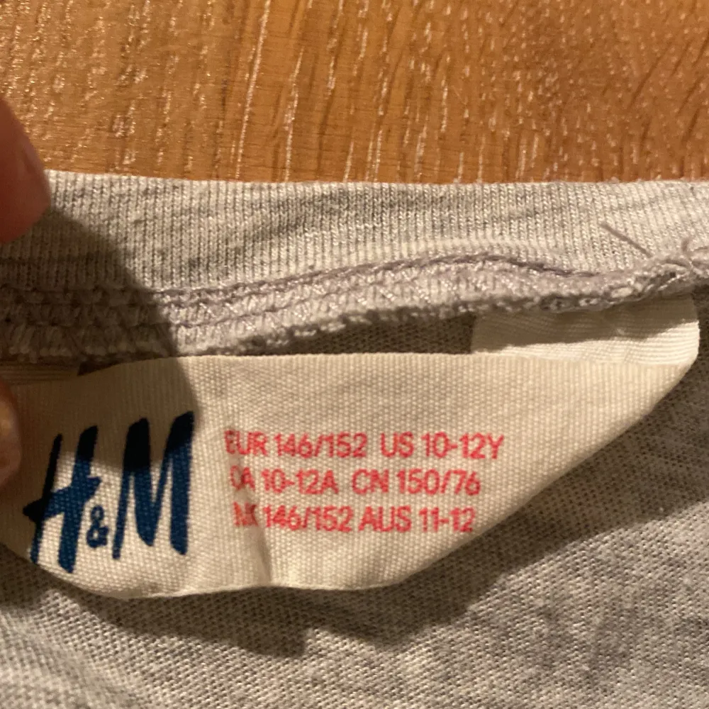 Säljer en grå t-shirt från H&M med ett stort svart A på framsidan. . T-paidat.
