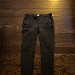 Mörkgrå kostymbyxor, Only and Sons - Snygga mörkgrå kostymbyxor/mjukisbyxor från Only & Sons. De har en klassisk design med knappar bak och en stilren passform. Perfekta för en dressad look. Uppskattar till storlek S/M