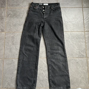 Svarta jeansbyxor - Snygga svarta jeansbyxor med hög midja och klassisk femficksdesign. De har en straight passform och knappar framtill. Perfekta för en stilren look.