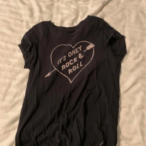 Svart t-shirt från Levi's - Snygg svart t-shirt från Levi's med tryck av ett hjärta och texten 'It's Only Rock & Roll'. Perfekt för en avslappnad stil med en rockig touch.