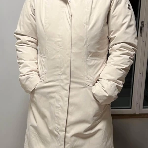 Vit parkajacka från The North Face - Säljer en vit parkajacka från The North Face. Jackan har en lång design med dragkedja och knappar framtill. Det är en 2-in-1-jacka (skaljacka + lättdunsjacka). Huvan går att ta av. Storlek L men innerjackan är lite liten i storlek. 