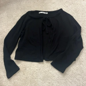 Svart kofta från 157 - Svart kofta från 157 i storlek XS. Koftan har långa ärmar och en knytning framtill. En tunnare kofta och knappt använd.