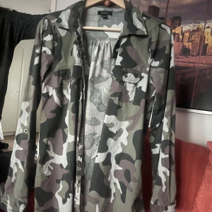 Camouflagejacka från Anive - Snygg camouflagejacka från Anive med långa ärmar och klassisk krage. Jackan har två bröstfickor med knappar och en avslappnad passform. Perfekt för en cool och avslappnad stil.💙