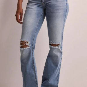 Ljusa jeans med slitningar från Nelly - Snygga ljusblå jeans från Nelly med slitningar på knäna. De har en bootcut-stil och är perfekta för en avslappnad look. Jeansen har en klassisk femficksdesign och stängs med dragkedja och dubbla knappar. St 32 men väldigt långa i benen, använda ca 3 gånger för dom är för små, så super bra skick!! Original priset är 700kr.