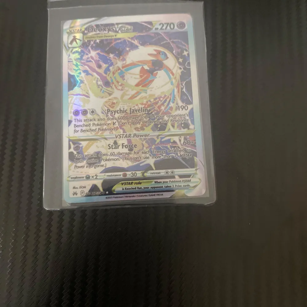 Säljer ett Deoxys VSTAR Pokémonkort med 270 HP. Kortet har attacker som Psychic Javelin och Star Force. Perfekt för samlare eller spelare som vill stärka sin kortlek. Kortet är i en skyddande plastficka.. Asusteet.
