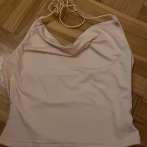 Beige halterneck linne - Säljer ett stilrent beige halterneck linne med draperad framsida. Perfekt för en somrig look. Passar bra till både jeans och kjol.