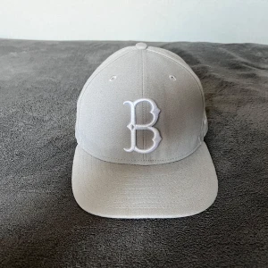 Grå keps från New Era - Säljer en snygg grå keps från New Era med ett broderat 'B' framtill. Kepsen är en del av Cooperstown Collection och har en klassisk design med en rak skärm.
