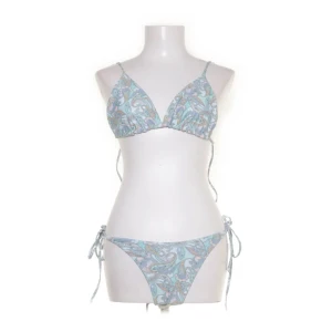 Mönstrad bikini med knytband - Snygg bikini i ljusblått med paisleymönster i pastellfärger. Köpta på sellpy, tvättade av mig och sedan aldrig använda. 