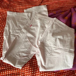 Rosa bootcut byxor med hjärtdetalj - Snygga ljusrosa byxor från Lucy med en söt hjärtdetalj vid fickan och ett stort diskret hjärta på rumpan med sömmarna. Dom sitter lågmidjat och bootcut. Har några små fläckar längst ner på ena benet! Midjemåttet tvärs över är 42 cm och innerbensmåttet är 82 cm!!❤️❤️