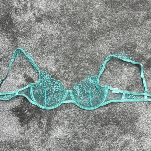 Turkos spets-bh - Säljer en elegant turkos bh med vacker spetsdesign. Bh:n har justerbara axelband och en blommig spetsdetalj som ger en romantisk känsla. Perfekt för att känna sig extra fin.