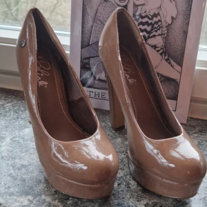 Beige pumps med klack och platå - Platform pumps i beige lack från 2010-talet. Har små skavanker där lacken har lossnat (syns på bilden) men de är i övrigt i bra skick då de inte använts så mycket. Platån gör att de är rätt lätta att gå i trots höjden på klacken. :) Små i storleken så skulle säga att de är mer som 37,5:or! 