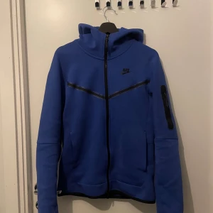 Blå hoodie från Nike - Säljer en snygg blå hoodie från Nike i storlek XS. Den har en dragkedja framtill och en praktisk ficka på ärmen. Perfekt för höst och vår, med en stilren design och bekväm passform. Passar både till träning och vardagsbruk.💯💯
