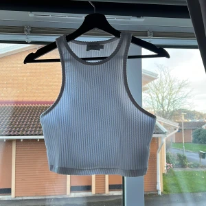 Vit ribbad linnetopp från NA-KD - Säljer en superfin vit ribbad linnetopp från NA-KD. Perfekt för sommardagar eller som ett lager under en jacka. Toppen är i mycket bra skick och har en tight passform som framhäver figuren. Den ärmlösa designen gör den både bekväm och stilren.