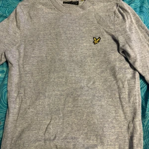 Grå tröja från Lyle & Scott - Säljer en stilren grå tröja från Lyle & Scott i bra skick. Den har en liten broderad logga på bröstet och är perfekt för både vardag och lite finare tillfällen. Tröjan är långärmad och gjord i ett mjukt material som känns skönt mot huden. Strl 170 S