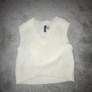 Vit stickad väst från Cropp - Säljer en superfin vit stickad väst från Cropp i storlek XS. Den har en v-ringad design och är perfekt för lager-på-lager under hösten. Västen är i mycket bra skick och passar både till vardags och fest. Perfekt för att hålla sig varm och stilren! 🤍