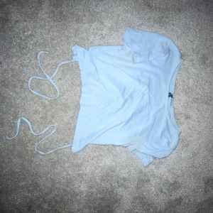 Vit croppad topp med knytband - Säljer en söt vit croppad topp med knytband i sidan. Perfekt för sommardagar eller en avslappnad fest. Toppen är i bra skick och har en enkel, stilren design.