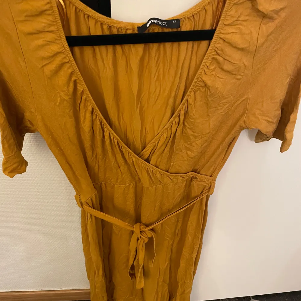 Säljer en superfin gul omlottklänning från Gina Tricot. Den har en v-ringad design och knytband i midjan för en smickrande passform. Perfekt för vår och sommar! Klänningen har korta ärmar och är i ett mjukt material som känns skönt mot huden. Hör av er för fler bilder eller frågor 🤍. Mekot.