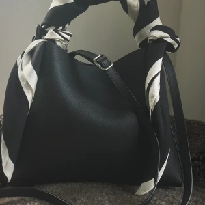 Svart väskband med silver spänne - Väskbandet är svart och har eleganta silvriga detaljer. Den är justerbar och har en  stilren design som passar till allt. Våra väskband är självklart helt nya och aldrig använda!💗