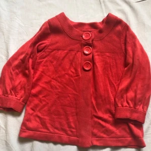 Röd kofta från H&M - Säljer en superfin röd kofta från H&M i storlek XS. Den är gjord av 100% bomull och har tre stora knappar framtill. Perfekt för höst och vår med sina trekvartsärmar och ribbade detaljer. Passar både till vardags och lite finare tillfällen. 🧶❤️finns några små fläckar på ärmen, se bild