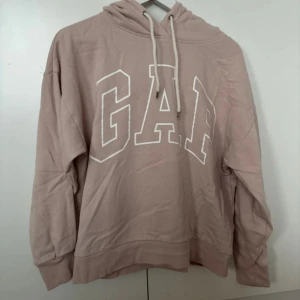 Rosa hoodie från GAP - Säljer en supermysig rosa hoodie från GAP i storlek M. Den har en klassisk design med stor logga framtill och en huva med dragsko. Passar till både jeans och mjukisbyxor!