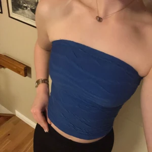 Blå tubtopp - Säljer en snygg blå tubtopp i ett stretchigt material💙Toppen är axelbandslös och har en tight passform som framhäver figuren. Den är i mycket bra skick och använd endast en gång, skriv för frågor! 