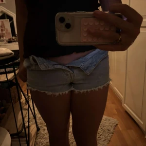 Ljusa jeansshorts med fransar - Säljer ett par ljusa jeansshorts i bra skick. De har en fransig kant och är perfekta för sommaren. Shortsen har en klassisk femficksdesign och stängs med knappar. Perfekta för en avslappnad dag på stranden eller en somrig utflykt. Säljer då dom är för små för mig