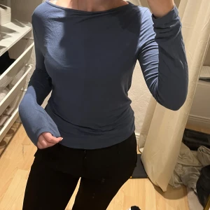 Blå långärmad topp - Säljer en snygg blå långärmad topp i mjukt material. Perfekt för både vardag och fest. Toppen har en enkel design med en bekväm passform. Passar bra till jeans eller kjol för en stilren look.