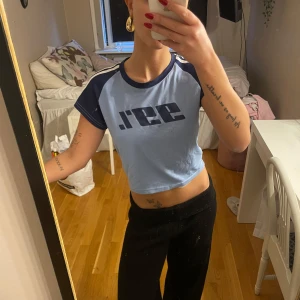 Blå croppad t-shirt - Säljer en cool blå och svart croppad t-shirt med trycket '99%' på framsidan. Den har korta ärmar med vita ränder längs axlarna. Den har en liten fläck på därför säljer jag till så lågt pris 🤍