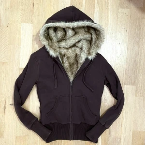 Brun hoodie med fuskpäls - Mysig brun hoodie med dragkedja och pälsfoder inuti. Fraktar elr möts upp! Färgen är brun och spegeln är smutsigt inte tröjan!