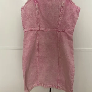 Rosa jeansklänning från H&M  - Rosa kort jeansklänning från H&M. Endast använd ett fåtal gånger och säljs därför.. Pris går att diskutera.