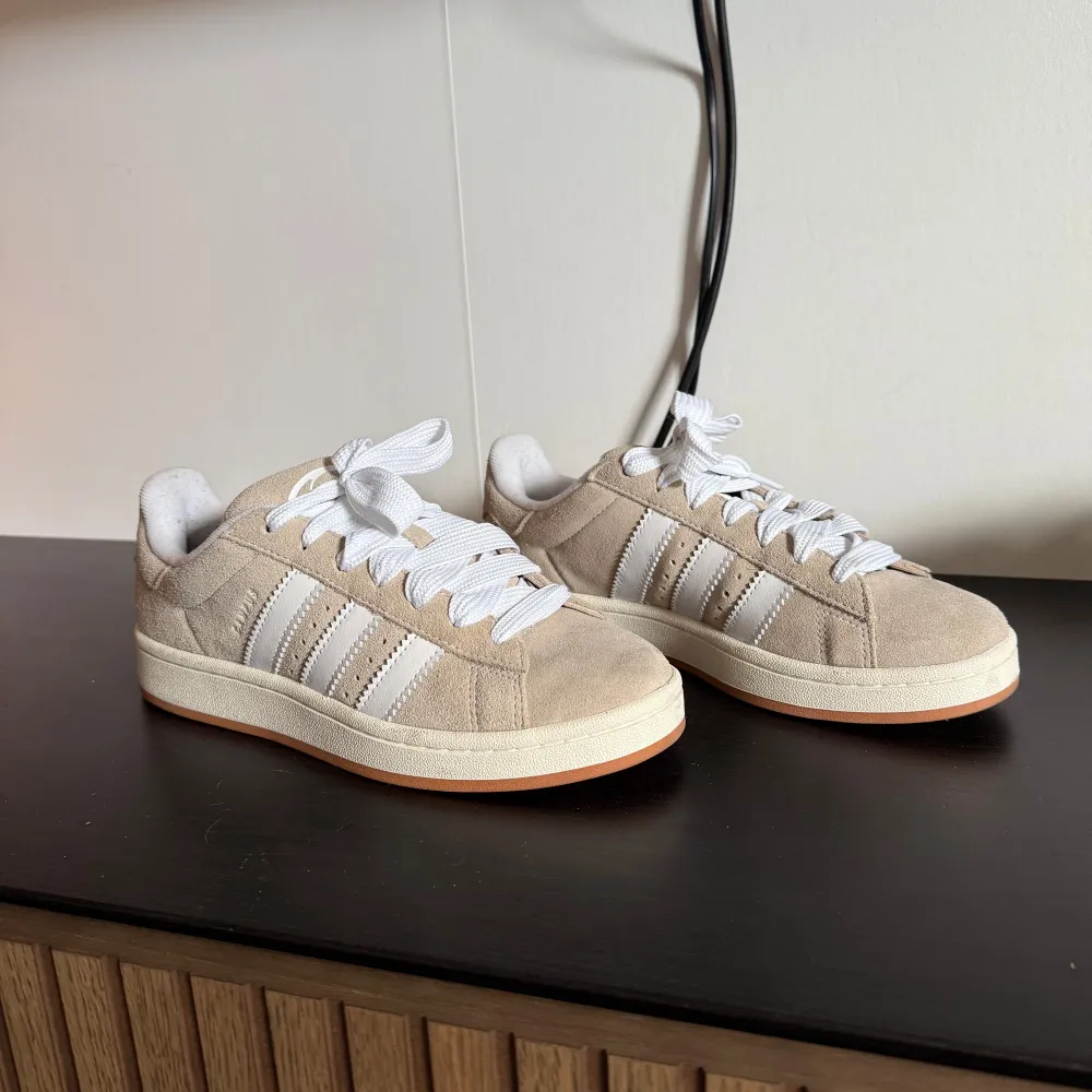 Adidas Campus 00S i färgen wonder beige.  I toppenskick! Storlek 39 1/3. Köpta från JD sports, kvitto finns om det önskas. Har tyvärr inte kvar orginalkartongen.  Både vita & beiga snören följer med 🥰🙏🏼. Skor.