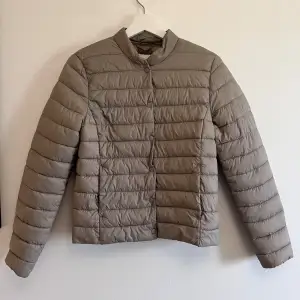 Säljer en snygg beige pufferjacka från H&M. Jackan är perfekt för höst och vår med sin quiltade design och långa ärmar. Den har en stilren look med knappar framtill. Superbra skick och redo för nya äventyr!