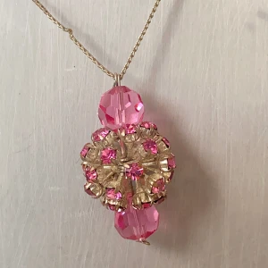 Halsband med rosa pärlor och gulddetaljer - Detta är ett supercharmigt halsband med en tunn kedja och flera rosa pärlor. Den har en stor, glittrig hängande detalj  med rosa stenar som verkligen fångar ögat. Perfekt för att lägga till en färgklick till din outfit!