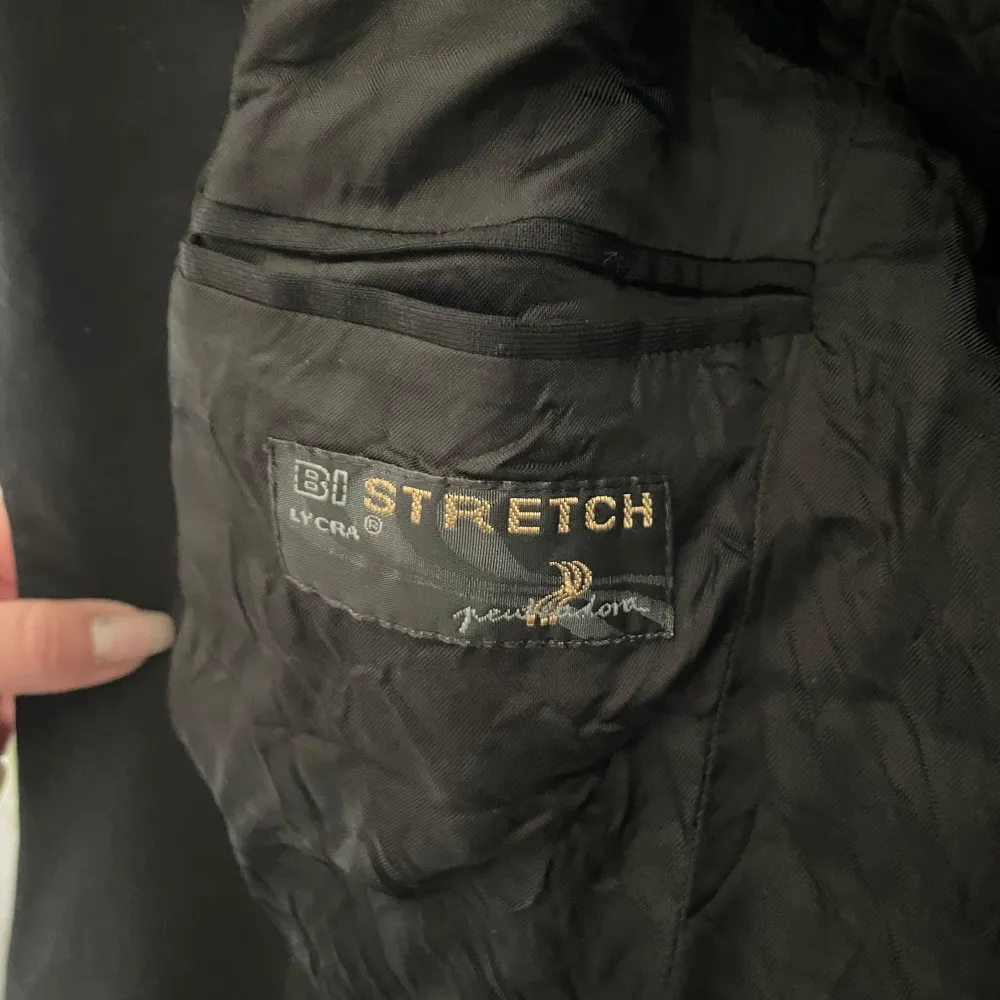 Säljer en klassisk svart kavaj från Pendleton i storlek 46. Den är tillverkad i en ullblandning med 60% ull och 2% elastan för extra stretch och komfort. Perfekt för både formella tillfällen och vardagsbruk. Kavajen har en stilren design med knappar framtill.. Puvut & Bleiserit.